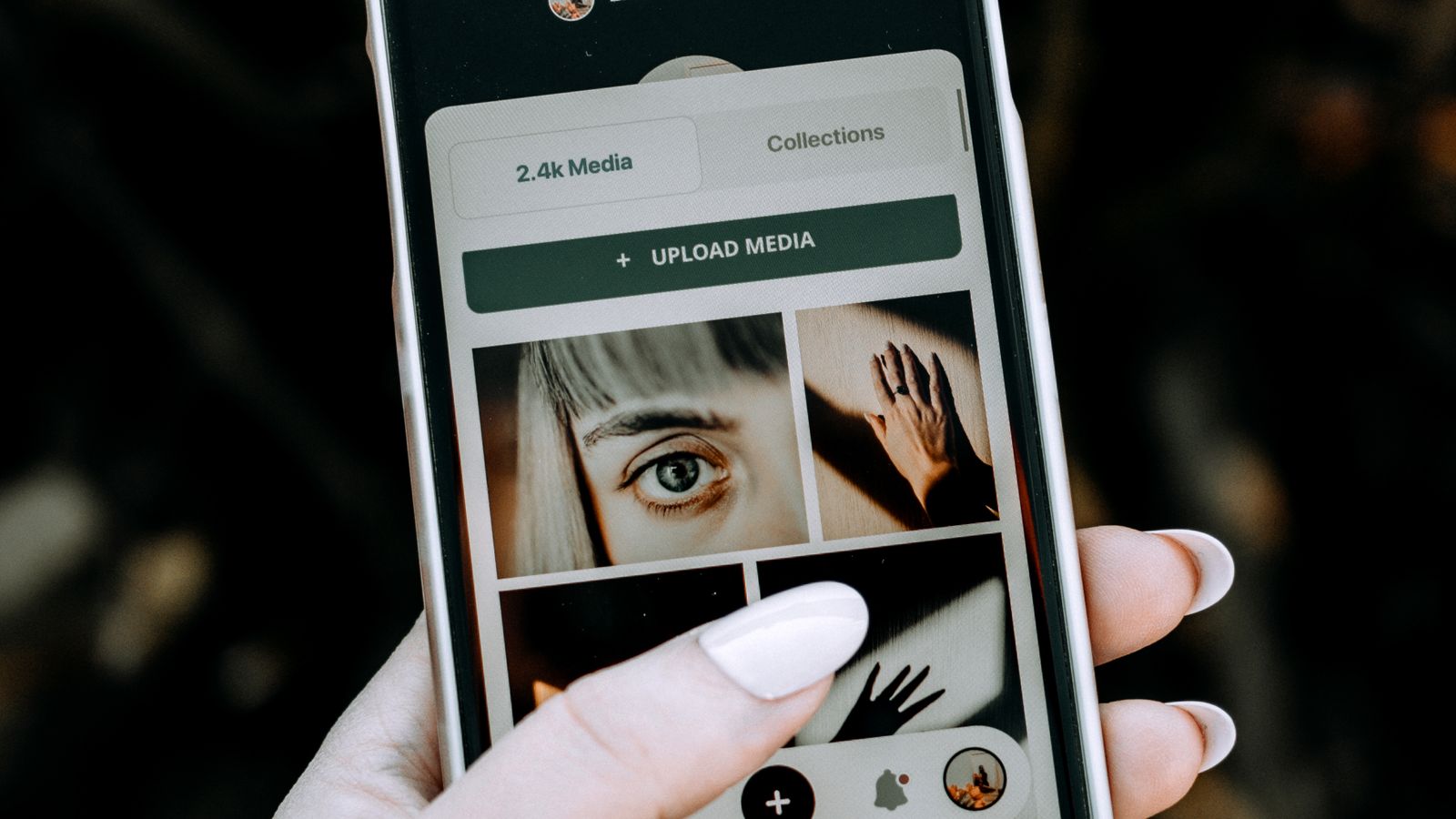 A hand holding a smartphone showing a photo gallery app, an example of reaching a family tree from a phone
