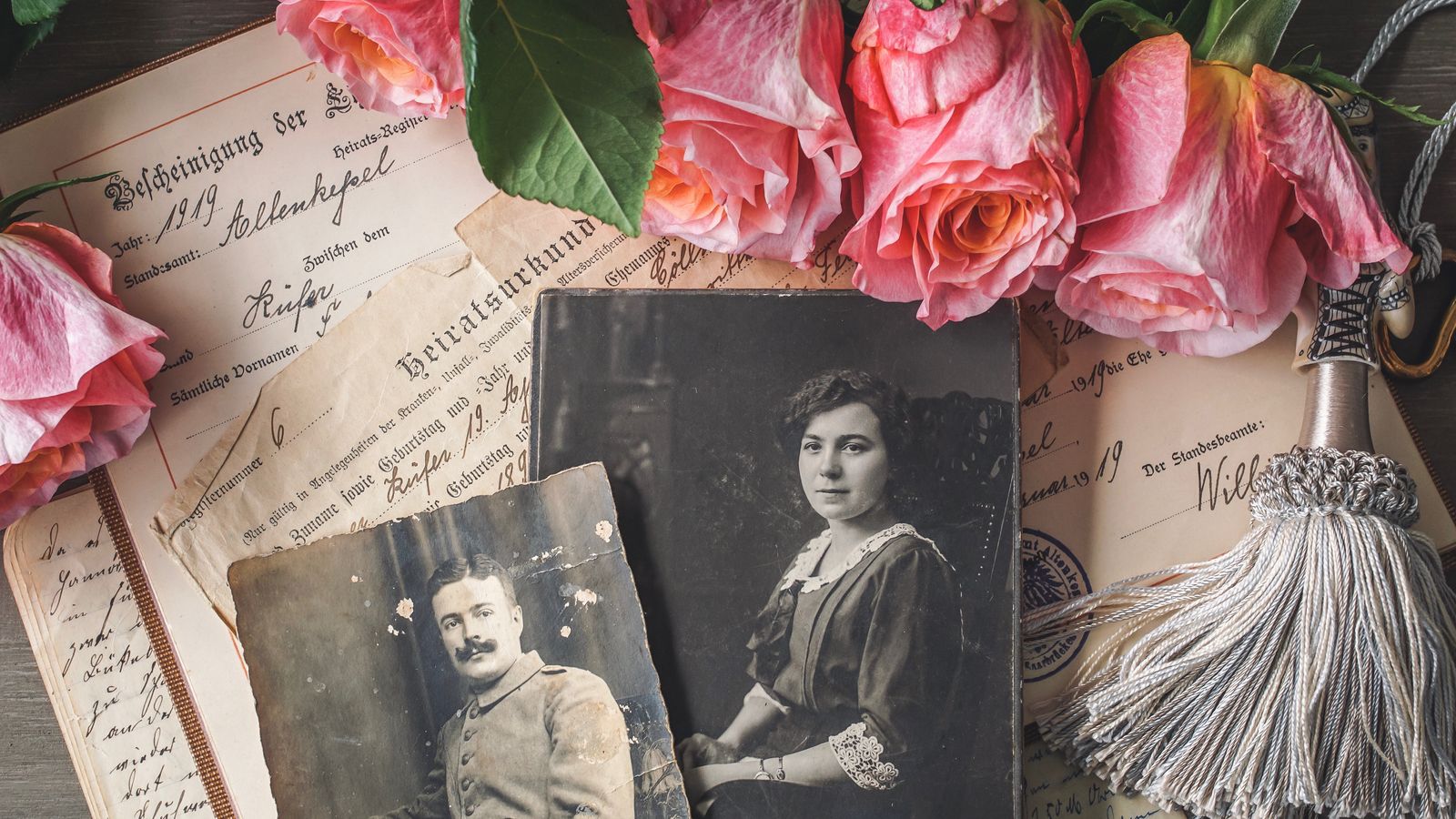 Old family photographs and heritage documents laid out on a table as the starting material for building a family tree