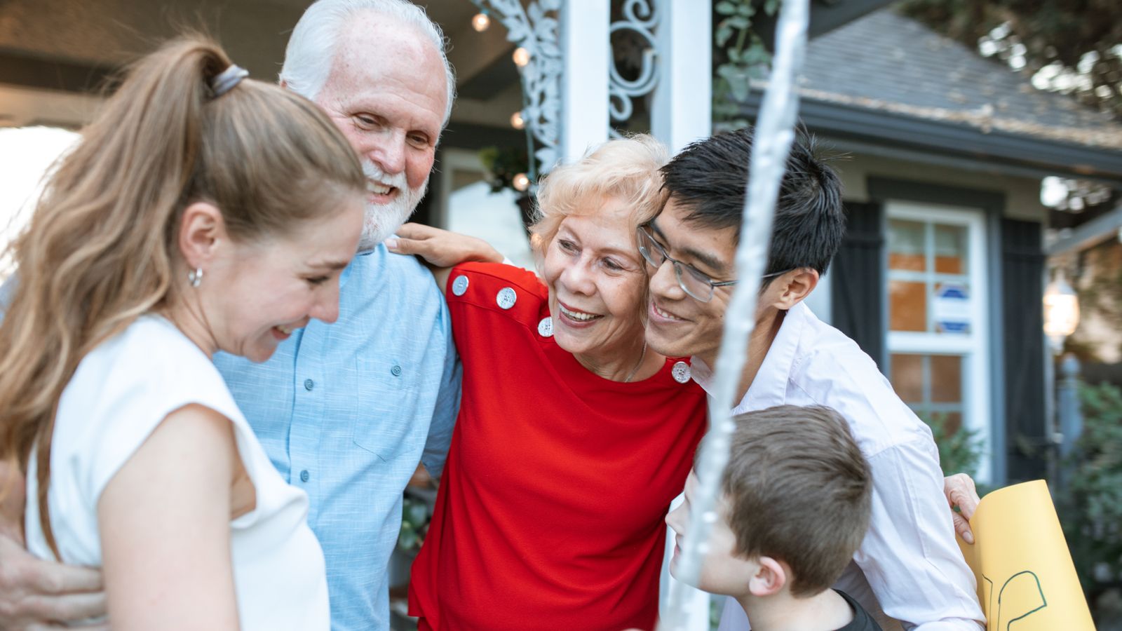 Family members of several generations embracing outside a house, the everyday situation in which a relationship has to be explained