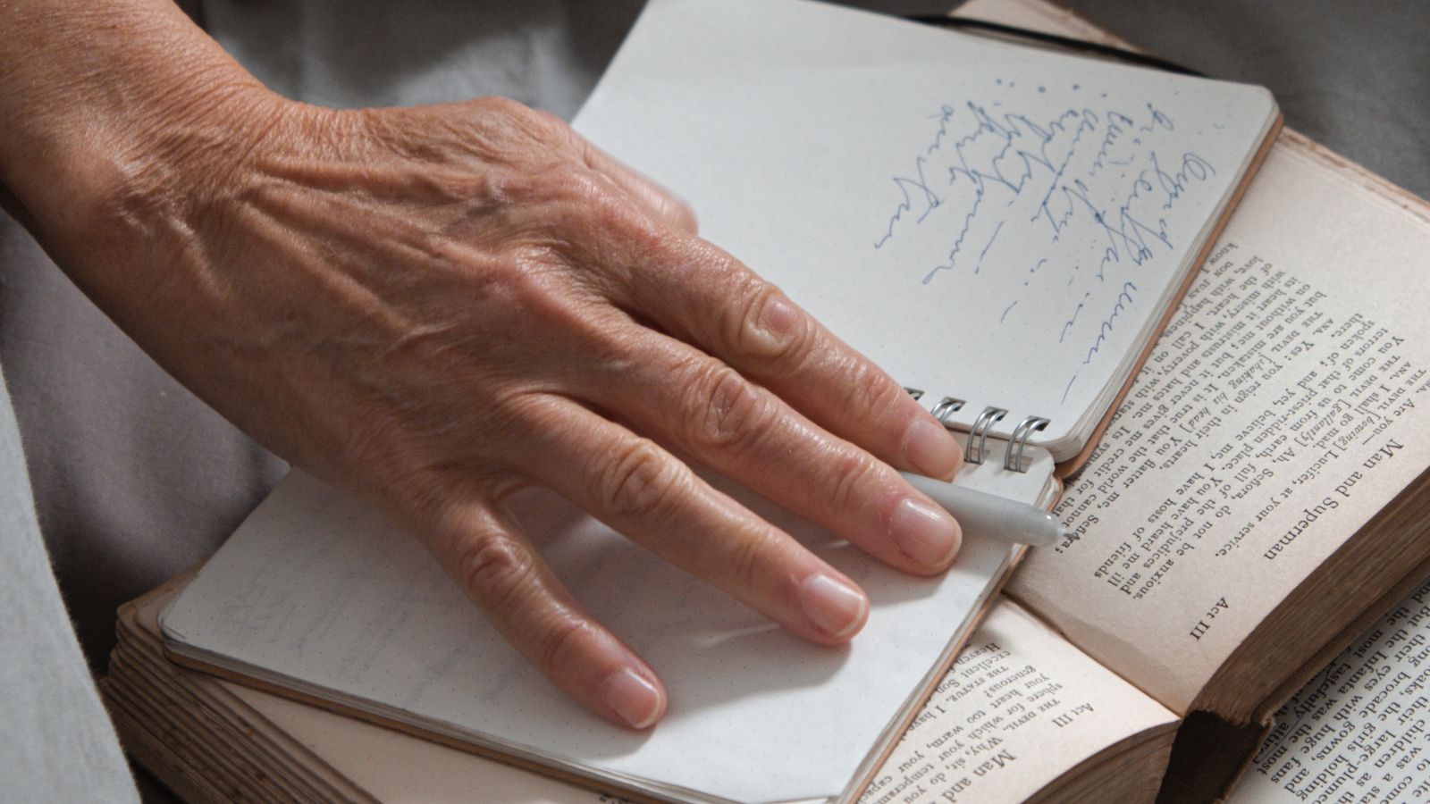 The hands of an elderly person writing in a notebook, capturing family stories and memories before they are lost