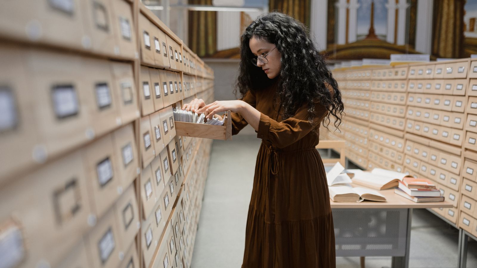 A woman leafing through catalogue cards in an archive room while searching for old official records