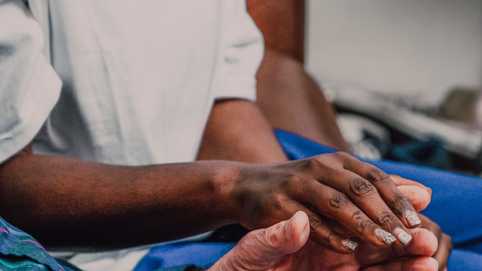 A volunteer holding an elderly person's hands in support, the spirit behind a family bereavement fund